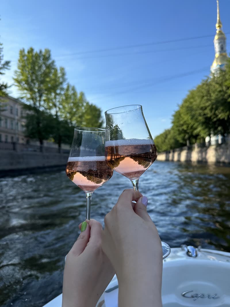 Два бокала розового игристого над водой канала, вдали купола Никольского собора